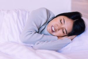 Young woman sleeping uncomfortably with bruxism symptoms
