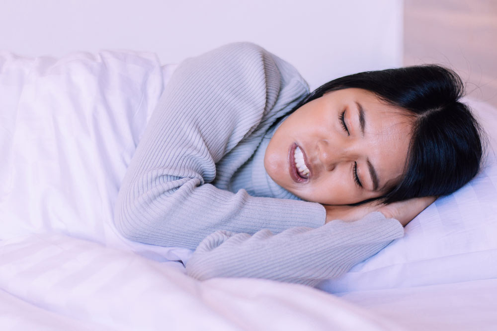 Young woman sleeping uncomfortably with bruxism symptoms