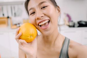 Smiling young woman holding a super healthy orange
