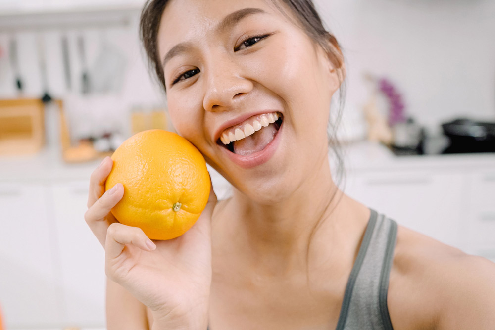 Smiling young woman holding a super healthy orange